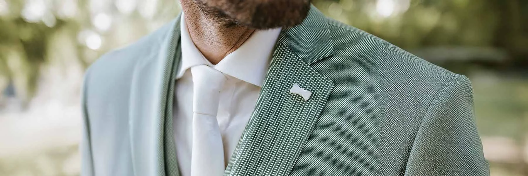 Detail van groen trouwpak met wit overhemd en das