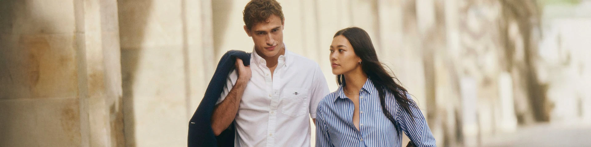 Man in wit overhemd met blazer over de schouder in old money stijl, tijdloze en ingetogen herenmode