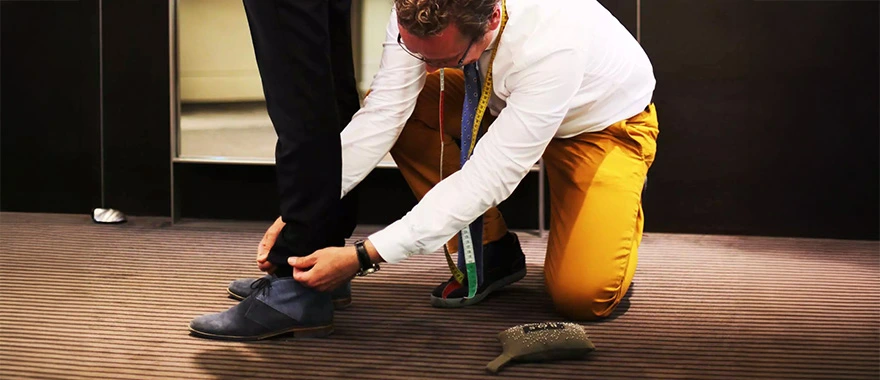 Medewerker van Bos Men Shop helpt een klant met het passen van herenkleding