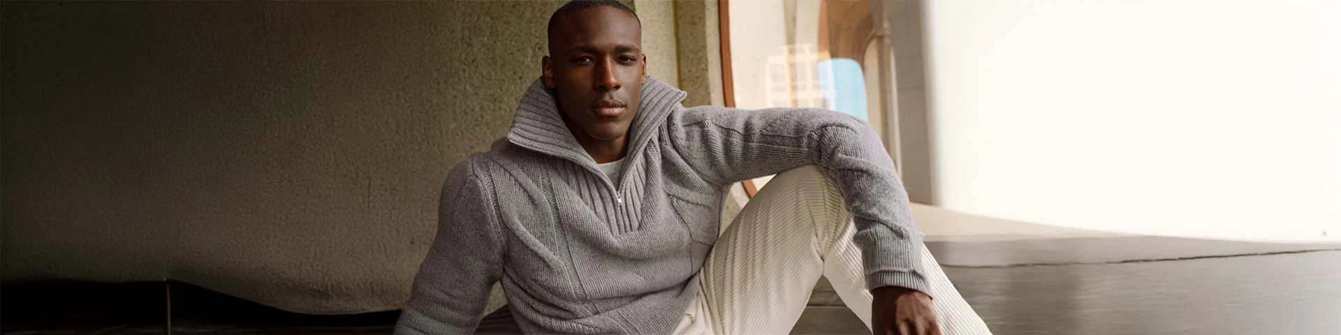 Man draagt een grijze wollen trui die zorgvuldig onderhoud en juist wassen van wol benadrukt