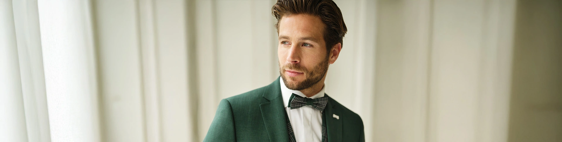 Bruidegom in donkergroen trouwpak met strik